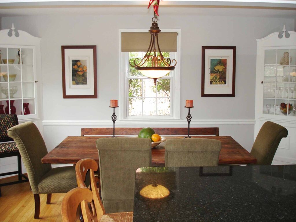Dining room staged for sale featuring a wooden table with bench and chairs, glass globe chandelier, and floral artwork